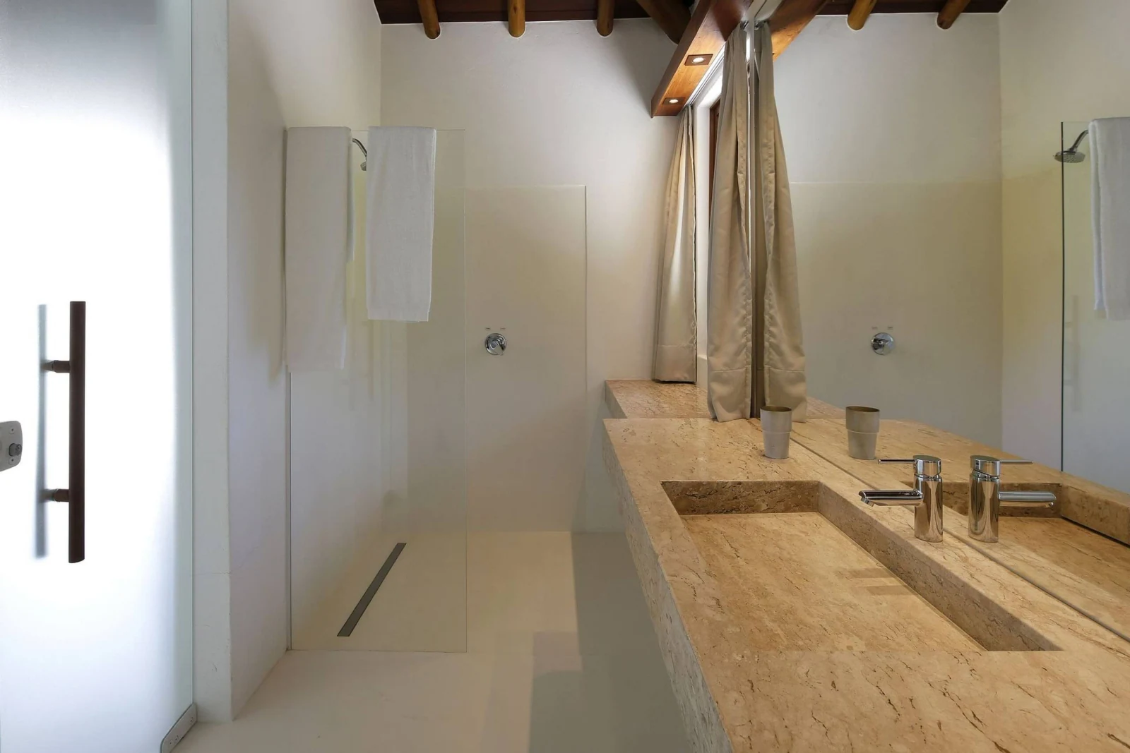 Banheiro em travertino com bancada comprida, mansão de luxo em Trancoso
